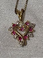 Close-up of heart-shaped pendant showing ruby and diamond accent stones with gold plating