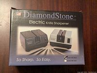 Front of box showing Diamond Stone Electric Knife Sharpener in black and silver with text and model options.