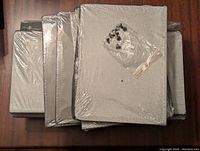 Top view of multiple fabric drawer units stacked and shrink-wrapped, with assembly hardware bag placed on top.