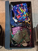 Image of the rectangular blue fabric storage box with many colorful cloth reusable gift bags inside.