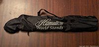 Black nylon carrying bag for the Hamilton music stand, featuring drawstring and white embroidered text.