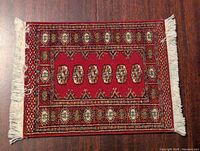 Front side showing red patterned mouse pad designed like a traditional rug with fringed edges.