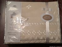 Front view of the unopened Victoria duvet cover in beige with detailed embroidered geometric pattern and packaging label.