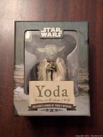 Front view of boxed Star Wars Yoda figure with label showing included wisdom quote book