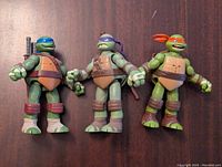 Front view of three TMNT figures: Leonardo, Donatello, Michelangelo, showing color details and articulation.