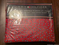 Front of unopened Tommy Hilfiger twin sheet set packaging showing red sheet with floral pattern and brand logo.