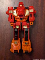 Front view of the figure showing prominent orange, red, black colors and gold stickers.