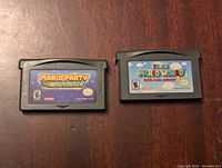 Front view of two Game Boy Advance cartridges for Mario Party Advance and Super Mario World: Super Mario Advance 2 showing game labels and ratings.