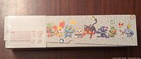 Side view of the sealed Pokemon TCG accessories box showing various Pokemon icons and characters.