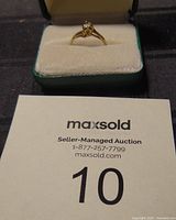 Ring displayed in its box alongside auction lot card