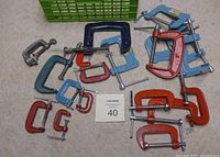 Assorted C clamps laid out on the floor showing size variation and colors including red, blue, grey, and teal.