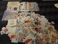 Large assortment of Canadian postage stamps scattered across a black surface showing diverse designs and colors.