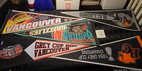Five vintage sports pennants laid out on table showing condition and full view of graphics and logos.