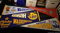 View showing five vintage sports pennants themed around Washington Huskies and Washington State University with some wear visible.