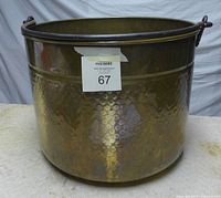 Full view of the large round brass cauldron, showing its hammered texture and patina.
