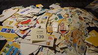 Large pile of numerous used Canadian stamps on torn envelope pieces, showing various designs and sizes.