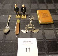 Full lot showing spoon with possible gold nugget, two Marx painted president figurines on rectangular bases, folding pocket knife with brown handle, Zenith service branded switchblade keychain knife, brown embossed leatherette case, and auction card.