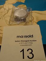 Silver Superman coin in plastic sleeve on superhero-themed backing.