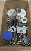 Various solder rolls, flux containers, and tools inside a cardboard box