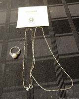 Ring and chain set on black fabric with lot number card