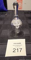 Full view of Swarovski crystal bell standing on table with auction tag 217.