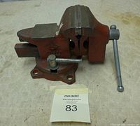 Side view of the bench vise showing the closed jaws, swivel base with 4-bolt mounting holes, and metal tightening handle.