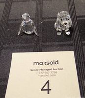 Photo showing the Swarovski crystal bird and dog ornaments on black fabric background alongside auction card