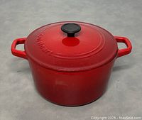 Front view of the red enameled cast-iron pot with lid and side handles.