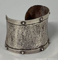 Front view of the hammered textured silver cuff bracelet studded with rivets showing overall shape and surface details.