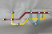 Front view of Umbra subway style multi-hook rack with red, yellow, and light blue colored metal strips and white circle hooks.