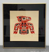Full framed artwork showing the stylized raven image in red and black with gold frame and black mat.