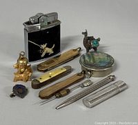 Lot arrangement photo showing all items including lighter, knives, pill box, charms, and tools for identifying vintage pocket tools and collectibles.