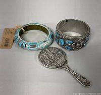 Photo shows all three items: the turquoise silver bracelet, Haida wooden bangle, and silver plated hand mirror.