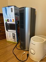 Four Seasons air purifier next to its box and a Honeywell humidifier on a floor surface.