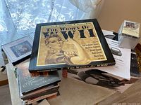 Photo showing the portable player, various CDs including The Women of WWII boxed set on top and additional CDs stacked underneath.