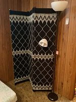 Photo of the three-panel metal framed screen with knit fabric and pattern, showing side view with floor lamp beside it