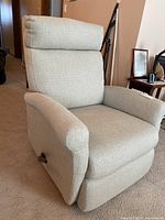 Front angled view of light gray recliner chair showing padded headrest and armrests, closed footrest