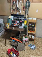 Overview photo showing large toolbox on table with various tools and items around it, including spool of string, wooden stool, and hanging cords.