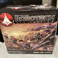 Front of the box showing Robotech RPG Tactics branding and colorful mecha battle artwork.