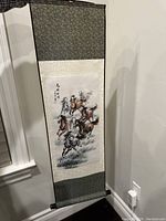 Full view of the hanging silk scroll with brush painting of horses.