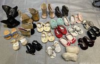 Overview of assorted American Girl doll shoes in various styles and colors arranged on a table.