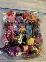 Clear plastic bag full of small assorted toys and figurines viewed from top showing mixed colors and characters.