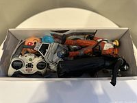 Top-down view of assorted Star Wars toys including figures and remote control packed in a white box.