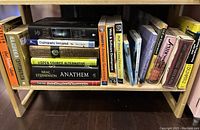 Books arranged on a wooden shelf including fiction and educational topics