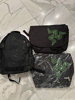 Three Razer laptop bags on marble floor, one backpack and two messenger bags.