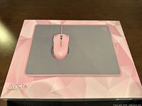 Photo of the Razer Invicta Quartz mousepad box with the mousepad visible on top, showing the pink and gray colors and the Invicta Quartz branding.