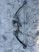 Full view of camo compound bow laid flat to show overall shape and condition