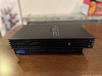 Front side view of the black PlayStation 2 Fat style console showing memory card and controller ports.