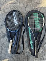 Two tennis rackets side by side, one Wilson and one Prince Thunder Lite, with their respective black carrying bags.