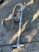 Full view of the Sharp EC-AX100 canister vacuum cleaner showing flexible hose, telescopic wand, and floor head on a stone surface.